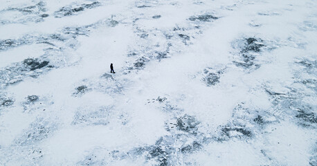 Aerial view from above on one person walks among an icy lake in winter
