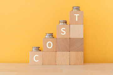 「COST」と書かれた積み木とコイン