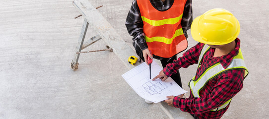 Fototapeta premium Architect and client discussing help create plan with blueprint of the building at construction site floor. Asian engineer foreman worker man and woman meeting and planning construction work, top view