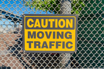 Caution moving traffic sign on a mesh fence at Coronado, San Diego, California