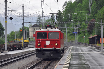 Electric locomotive arrives to the platform after rain. Filisur.