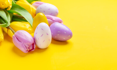 Fototapeta na wymiar Easter composition. Multicolored easter eggs and tulips on yellow background. Easter concept. Copy space