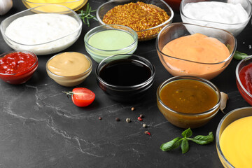 Many bowls with different sauces on black table