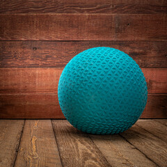 heavy rubber slam ball filled with sand on a rustic wooden background, exercise and functional fitness concept