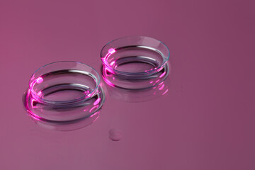 Pair of contact lenses on pink reflective surface. Space for text