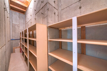 Unfinished narrow storage room with concrete walls and floors