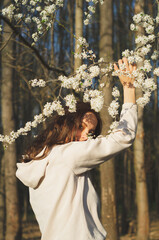 Portrait of young beautiful woman among flowering trees. A woman rejoices in spring flowers....