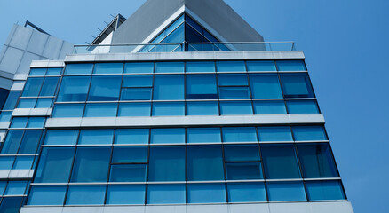 Obraz premium business building in city with mirror windows with reflections of blue sky.