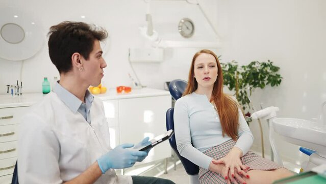 Male dentist discussing treatment options with female patient after dental examination