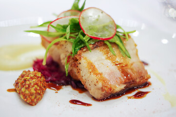 chinese crispy roasted pork belly with sauce and sliced radish on white plate