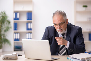 Fototapeta premium Old male employee working in the office