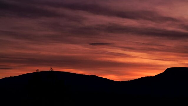 Impresionante toma panor&aacute;mica sobre la silueta del bosque y las monta&ntilde;as contra un hermoso cielo rojo p&uacute;rpura al atardecer.