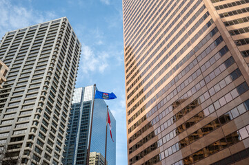 Fototapeta na wymiar Looking up at skyscrapers in the city of Calgary with Alberta and Canadian flags.