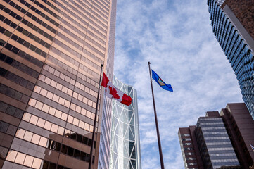 Looking up at skyscrapers in the city of Calgary with Alberta and Canadian flags.