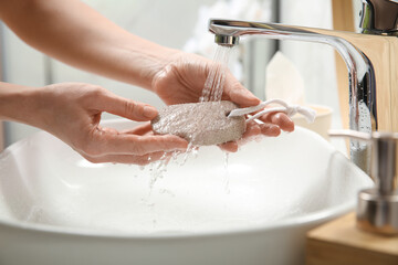 Woman pouring water onto pumice stone in bathroom, closeup