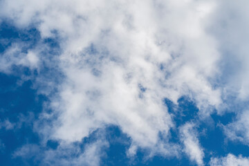 White fluffy cirrus clouds against the blue summer sky.