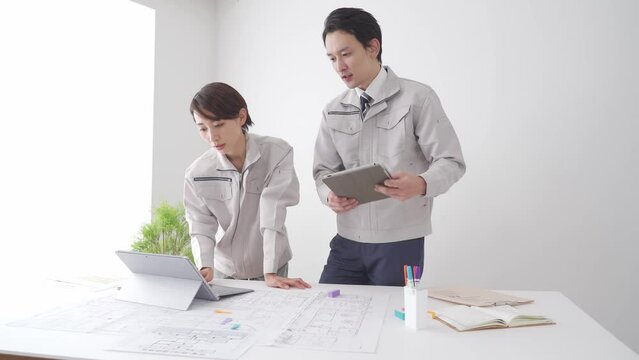 打ち合わせ・作業着を着たアジア人男女