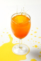 Splash of orange liquid in a glass from a thrown dice - 485470769