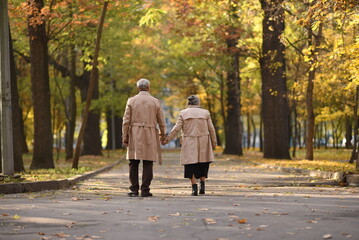 Old happy loving couple walks holding hands