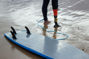 Close-up of sporty man getting ready to step into sea. Mid adult man with prosthetic leg standing...