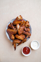 Plate of Barbecue chicken wings on  table with sauces. Top view. Copyspace