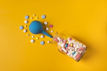 Pediatrics. Enema. Multi-colored pills in a bottle. Treatment of constipation in children. Cold treatment.
