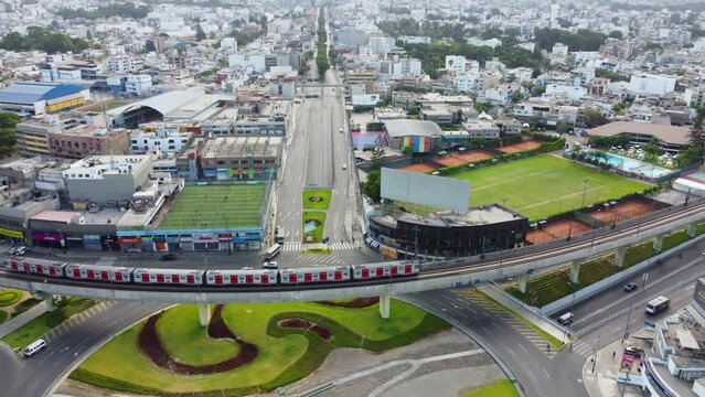 Red and white electrical train passing over a roundabout in Lima, Peru. Early morning time and light traffic.
