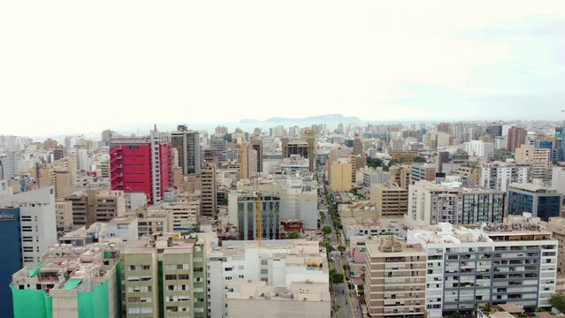 Drone 4k footage of cityscape. Many residential and bussiness buildings. Flying left to right. With horizon and ocean and island in the far background.