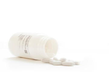 Closeup of a white pills and bottle, on white background with copy space
