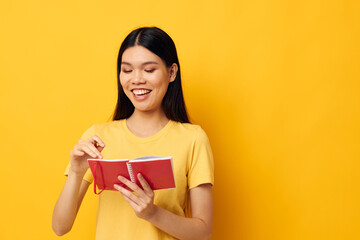 woman with Asian appearance in a yellow t-shirt red notebook training yellow background unaltered
