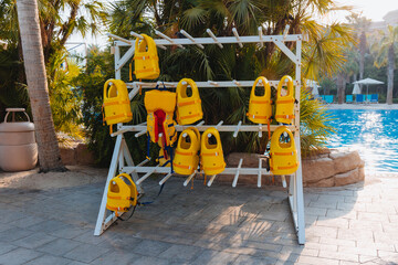 Stack of hanging yellow life vests on hangers outside during the marine activities, safety clothing, protection concept