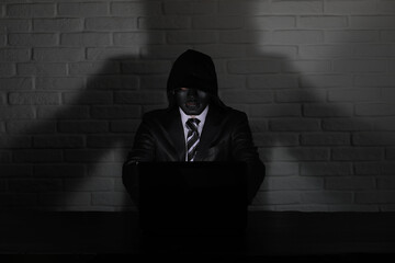 Hacker in black mask and hood at the table