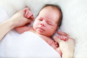 A newborn baby lies in her mother's arms. A beautiful baby of European appearance is sleeping.