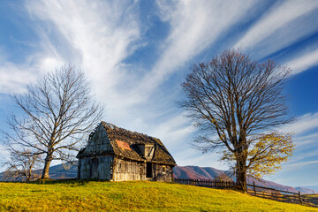 Old wooden house built on grassy hill against mountains