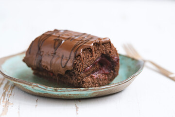 Chocolate cake with blackcurrant in ceramic plate on white wooden background.close up