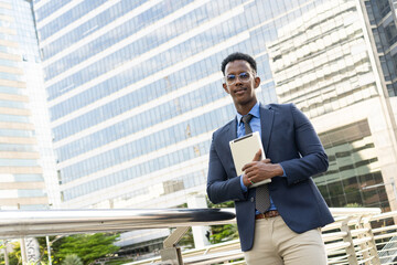 Business people in city. Portrait of an handsome businessman. Modern businessman. Confident young man in full suit and glasses while standing outdoors looking away with cityscape in the background