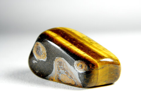 natural mineral gem stone - Tiger's eye (Tigers eye, Tiger eye) gemstone isolated on white background close up