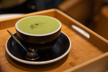 a cup of matcha green tea latte on a wooden tray