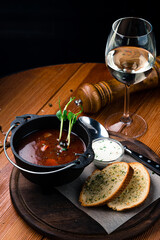 Pot of Red borscht with sour cream and bread croutons. Portion of Meat soup with beetroots