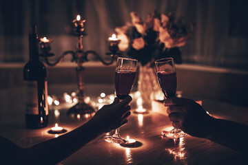 Hands man and woman holding glasses of wine having romantic candlelight dinner at table at home....