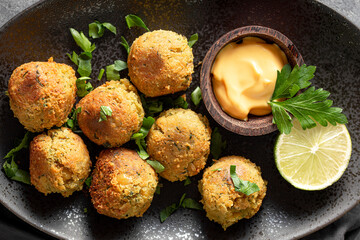 Chickpea falafel with sauce on black plate close up top view