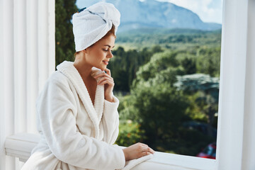 Portrait of gorgeous woman in a white robe on the balcony bit on green nature Relaxation concept