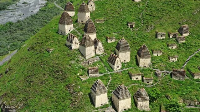 Aerial around view of Dead Town Dargavs In North Ossetia. The ancient cemetery of the Alans. Many small stone mausoleums, 4k