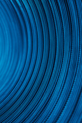Ridged abstract background. Blur color glow. Curved embossed texture. Defocused neon blue light on grooved striped futuristic overlay.