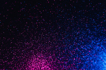 Color glitter overlay. Blur sparkles. Bokeh light. Night sky stars reflection. Neon blue magenta pink grain texture glow on dark black shimmering abstract background.