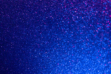 Neon glitter background. Bokeh glow. Defocused sparkles. Blur fluorescent light blue pink color...