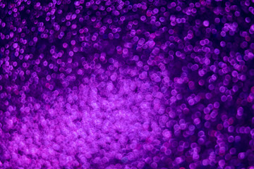 Fluorescent background. Bokeh light. Blur sparkles reflection. Defocused neon purple color glow circles texture on dark black abstract overlay.