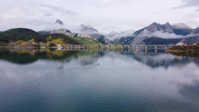 Tourist Supping at Lake Ria&ntilde;o, Leon, Spain - Aerial Drone View of Cloudy Mountains and Famous Bridge