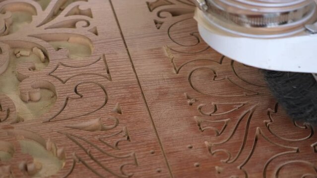 Woodworking CNC router machine cuts a pattern on a piece of wood.Close up,slow motion.