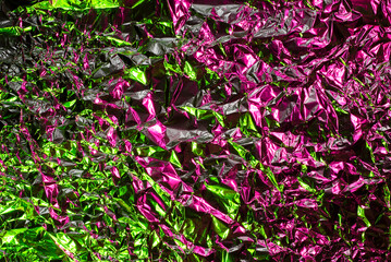 Green and pink aluminum wrinkled foil background. Abstract bright texture reflecting creative gradient. Light neon futuristic colors. Colorful shiny backdrop for screens, website, flyers and brochures